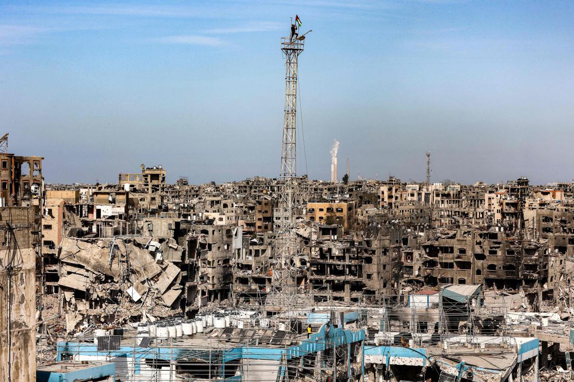 A man fixes a Palestinian flag atop the antenna of a destroyed building that was a clinic for the United Nations Relief and Works Agency for Palestine Refugees (UNRWA) at the Jabalia camp for Palestinian refugees in the northern Gaza Strip on January 19, 2025. (AFP)