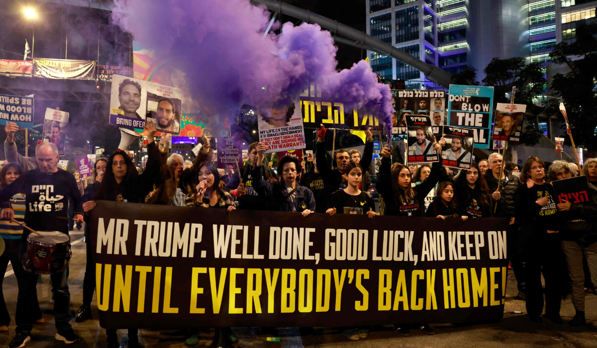 Supporters and relatives of Israeli hostages held captive in the Gaza Strip since the October 7, 2023 attacks by Hamas militants, hold a message addressed to US President Donald Trump during a demonstration in Tel Aviv on January 20, 2025, calling for an immediate end of the war and return of all the hostages. (AFP)