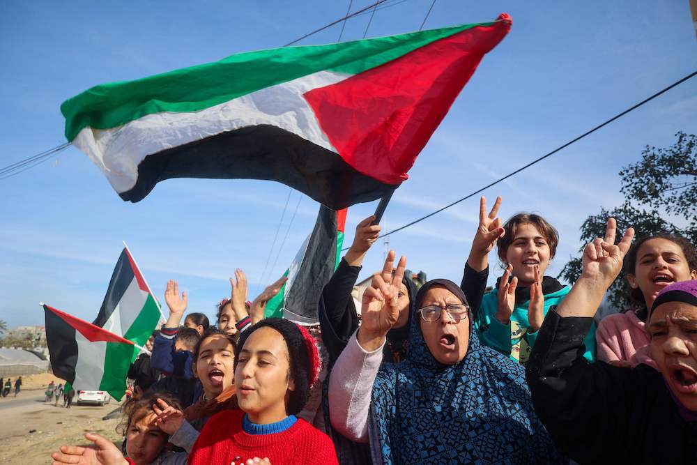 Displaced Palestinians wave national flags as they return to Rafah in the southern Gaza Strip, on Jan. 19, 2025, following a ceasefire deal in the war between Israel and Hamas. (AFP)