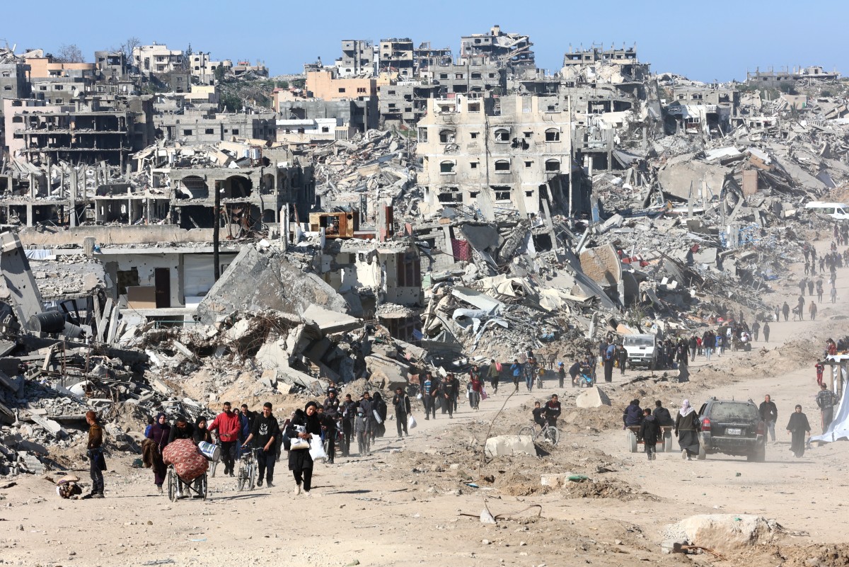 Palestinians walk in a street in Jabalia along the rubble of destroyed buildings as displaced head to the northern areas of the Gaza Strip, on the third day of a ceasefire deal in the war between Israel and Hamas, on January 21, 2025. (AFP)