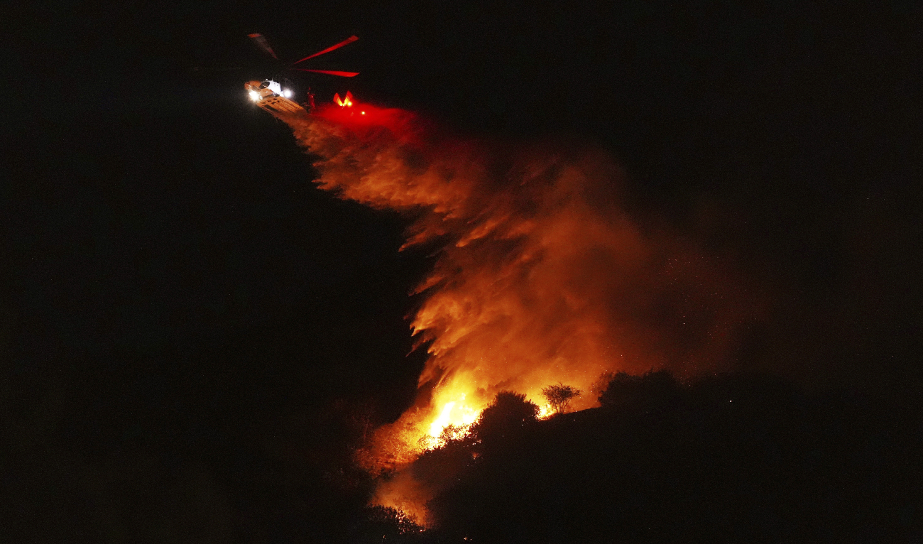 A helicopter drops water on a fire as it burns along Interstate 405, Thursday, Jan. 23, 2025, in Los Angeles. (AP)