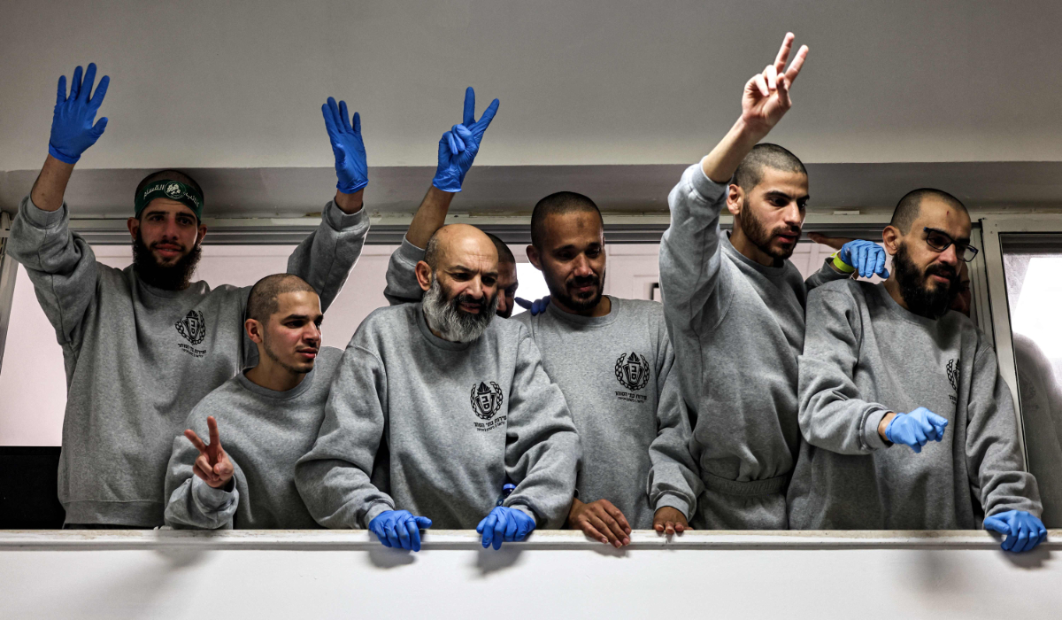 Palestinian prisoners released by Israel wave and cheer to people below gathering to receive them at a sports centre building of the Ramallah municipality, after arriving there aboard buses of the International Committee of the Red Cross (ICRC), in Ramallah in the occupied West Bank on January 25, 2025. (AFP)
