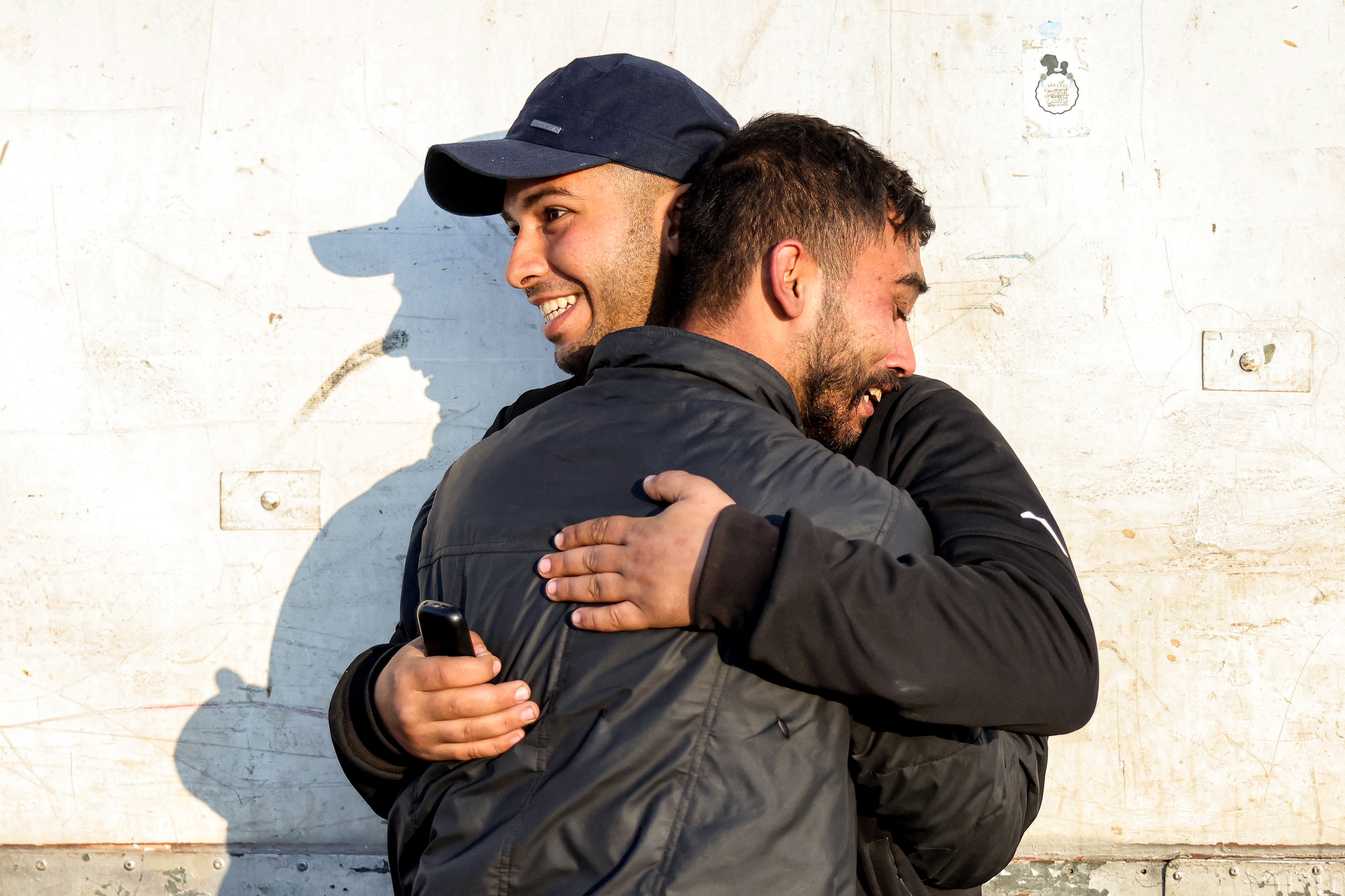 Palestinians embrace each other after crossing the Netzarim corridor from the southern Gaza Strip north into Gaza City along Gaza's coastal al-Rashid Street, Jan. 27 (AFP)