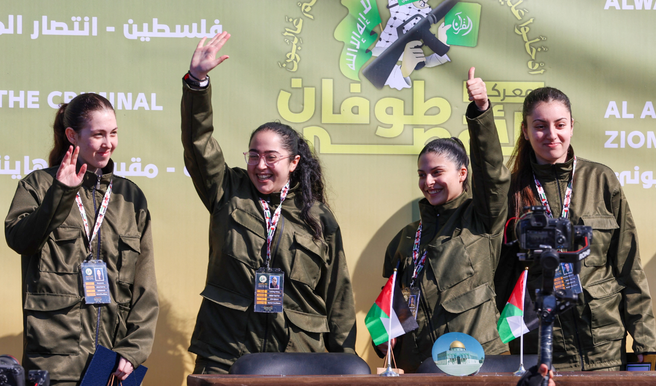Four Israeli hostages, (L-R) Naama Levy, Liri Albag, Daniella Gilboa and Karina Ariev, wave from a stage before Hamas fighters hand them over to a team from the Red Cross in Gaza City on January 25, 2025. (AFP)