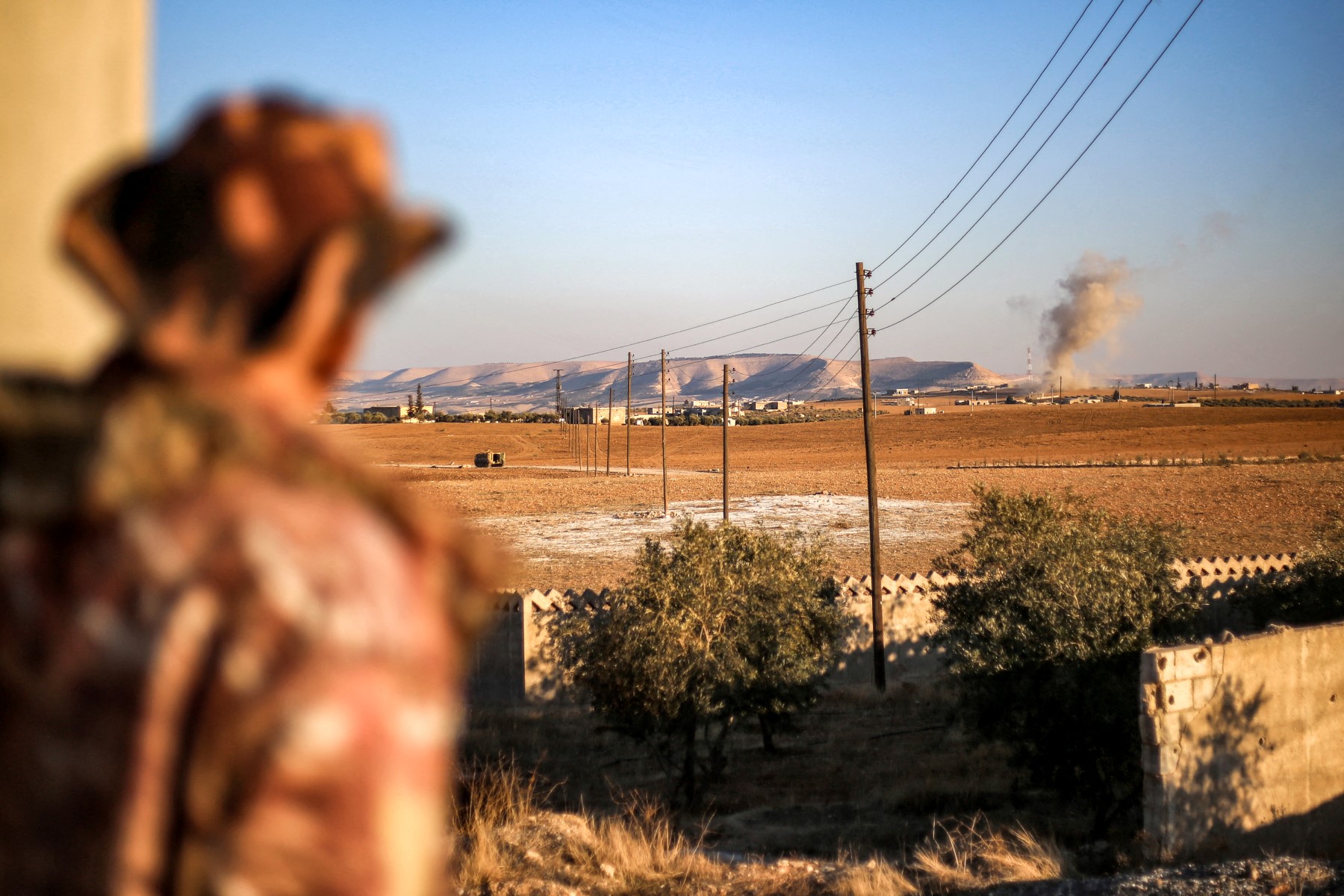 A fighter of the the Turkish-backed Syrian National Army faction watches a plume of smoke erupt from bombardment at a position near the Tishrin Dam in the vicinity of Manbij, in the east of Syria's northern Aleppo province, on January 10, 2025 amidst ongoing battles with the Kurdish-led Syrian Democratic Forces (SDF). (AFP)
