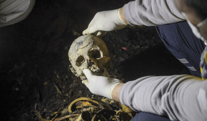 A Syrian civil defense worker, known as a White Helmet, holds a skull while inspecting human remains found in two separate basements in Sbeneh, outskirts of Damascus, Syria, on Jan. 28, 2025. (AP)