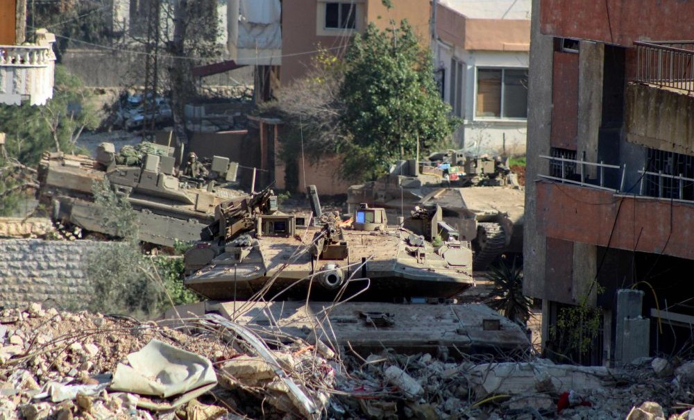 Israeli armored vehicles take position behind a barrier at the entrance to the southern Lebanese village of Aitaroun on January 29, 2025. (AFP)