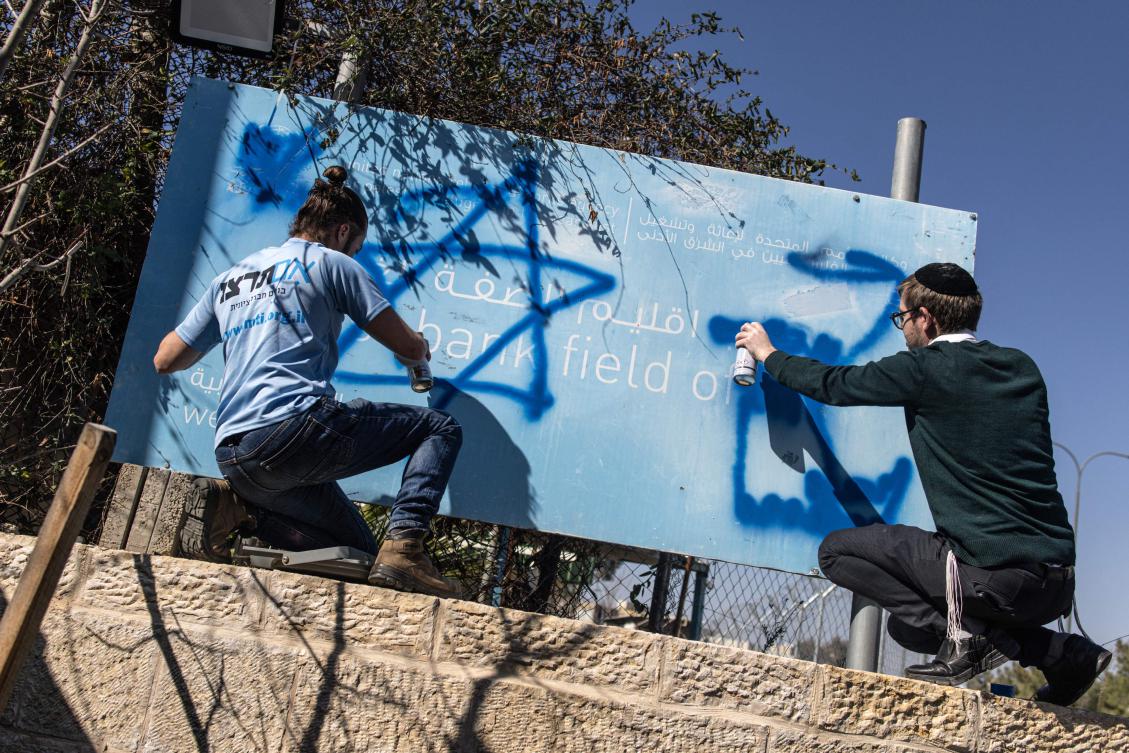 Israeli right wing activists deface the sign board in front of the shuttered gate of the United Nations Relief and Works Agency’s West Bank Field Office in Jerusalem on Jan. 30, 2025. (AFP)
