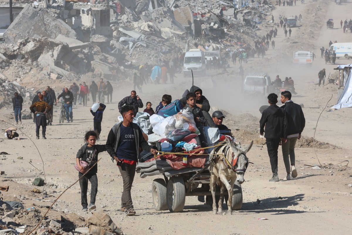 Palestinians transport belongings in Jabalia along the rubble of destroyed buildings (AFP)