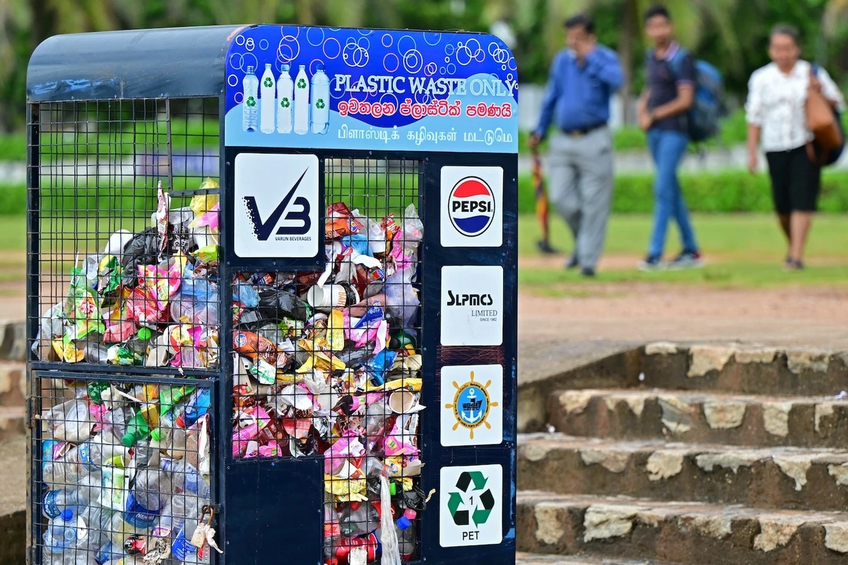 Pedestrians walk past a trash can filled with plastic waste along a street in Colombo, Sri Lanka, on Nov. 26, 2024. (AFP)