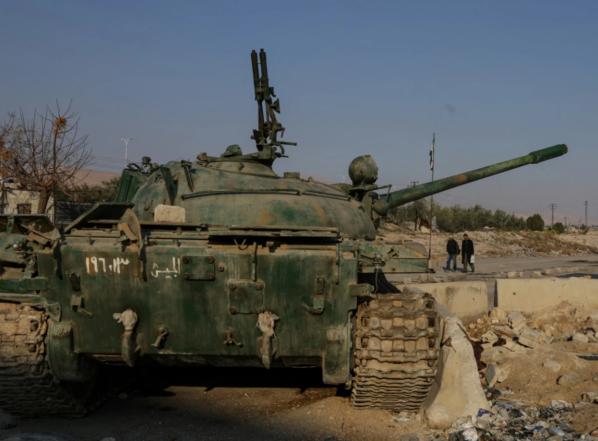 Men walk near an abandoned tank that belongs to the ousted Syrian President Bashar al-Assad's forces, on the outskirts of Damascus, Syria, on January 2, 2025. (REUTERS)