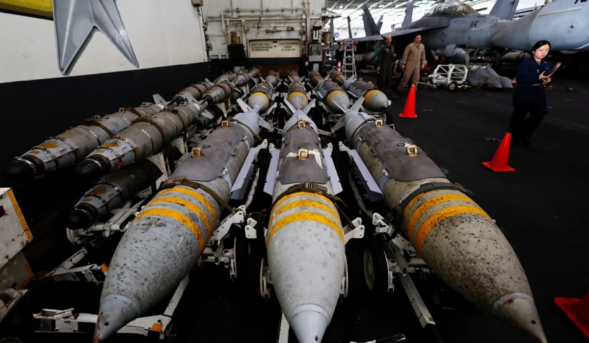 US Navy staff members walk next to aerial bombs at the hanger-bay aboard the USS Dwight D. Eisenhower (CVN 69) aircraft carrier in Southern Red Sea, Middle East, February 13, 2024. (Reuters))