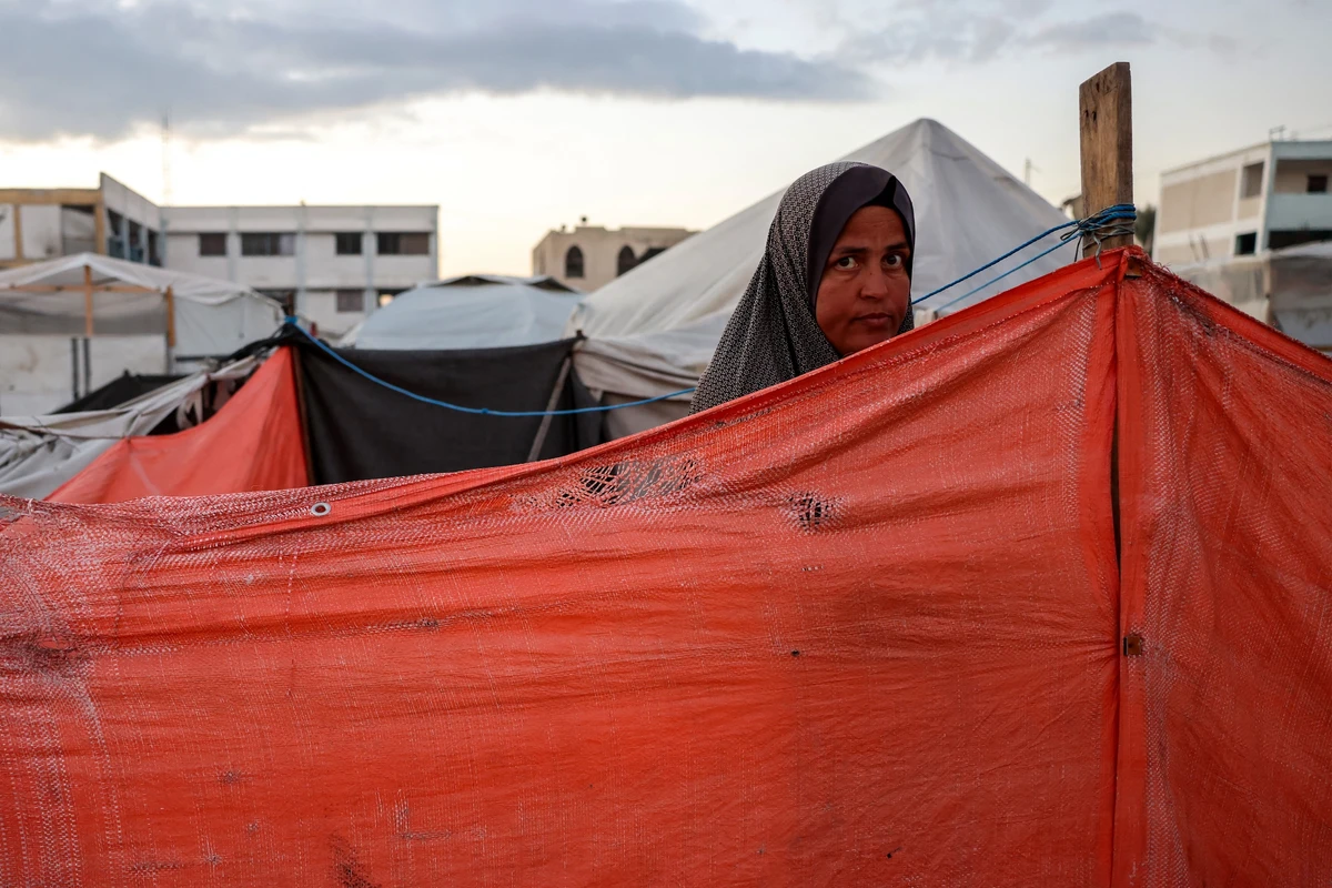 A woman looks on from behind a shelter at a camp for displaced Palestinians in Khan Yunis, in the southern Gaza Strip on Dec. 29, 2024 (AFP)