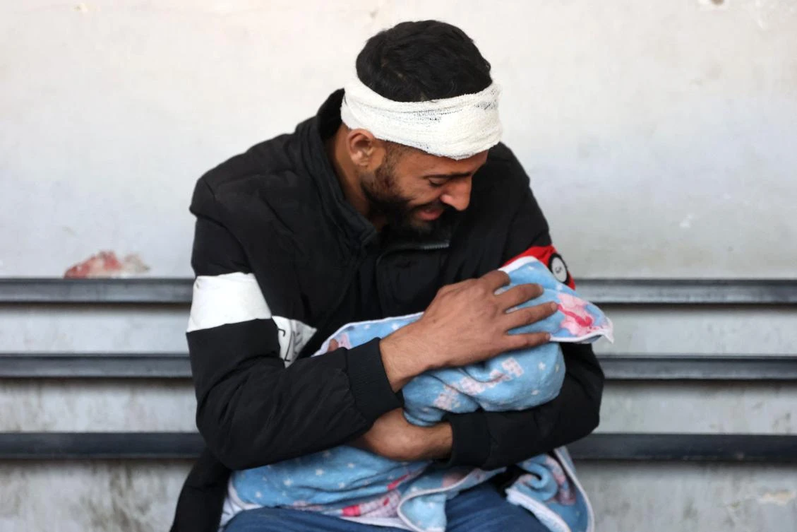 Palestinian Bilal Kallab cries as he holds the body of his 17-day-old baby Adnan, after he was killed during an Israeli strike in Gaza City, on January 8, 2025, at Ahli Arab hospital, also known as the Baptist hospital, amid the ongoing war in the Palestinian territory between Israel and Hamas. (AFP)