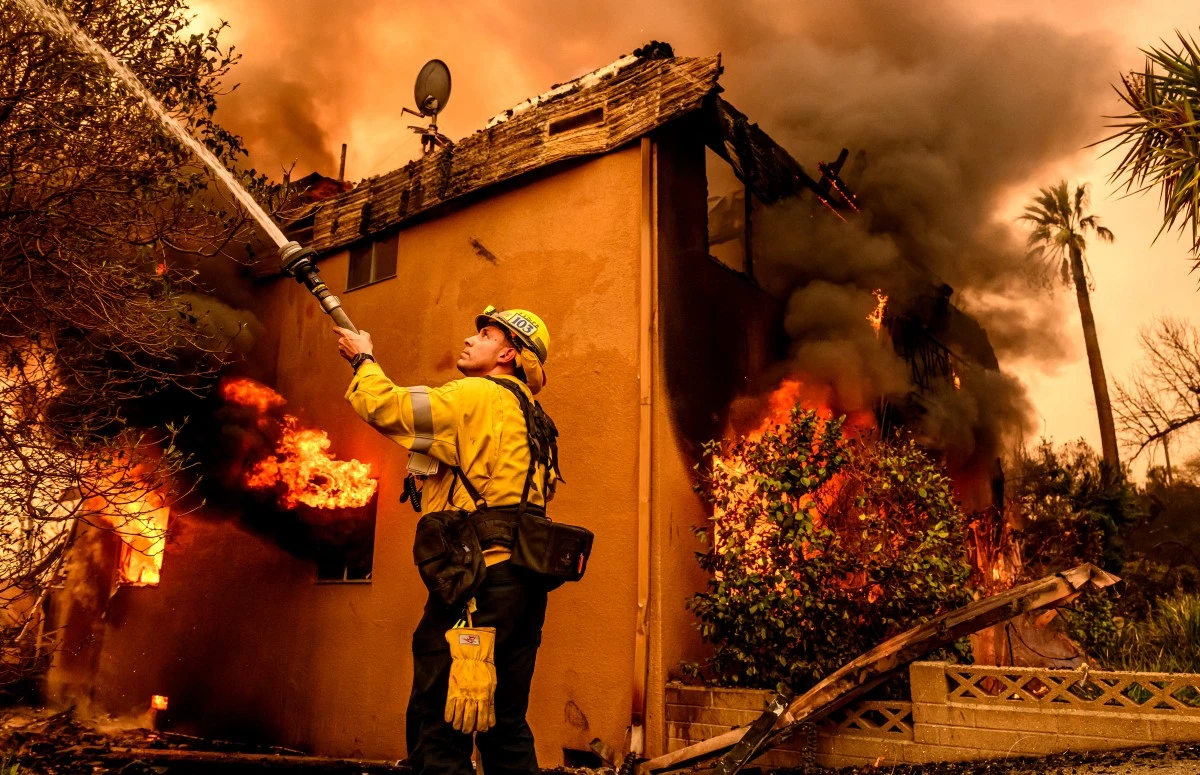 A firefighter douses flames as an apartment building burns during the Eaton fire in the Altadena area of Los Angeles county, California, Jan. 8 (AFP)