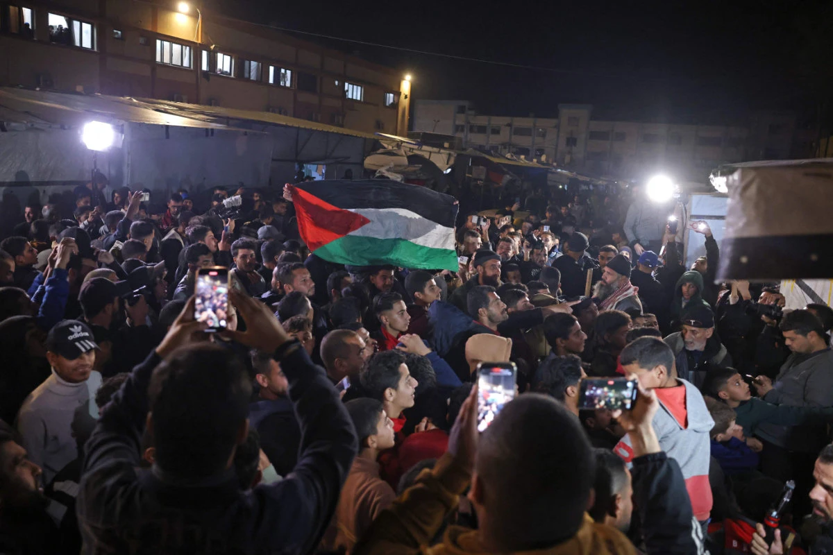 Palestinians watch a television along a street in Khan Yunis in the southern Gaza Strip on January 15, 2025, as news is broadcast that Israel and Hamas have agreed on a ceasefire and hostage release deal. (AFP)