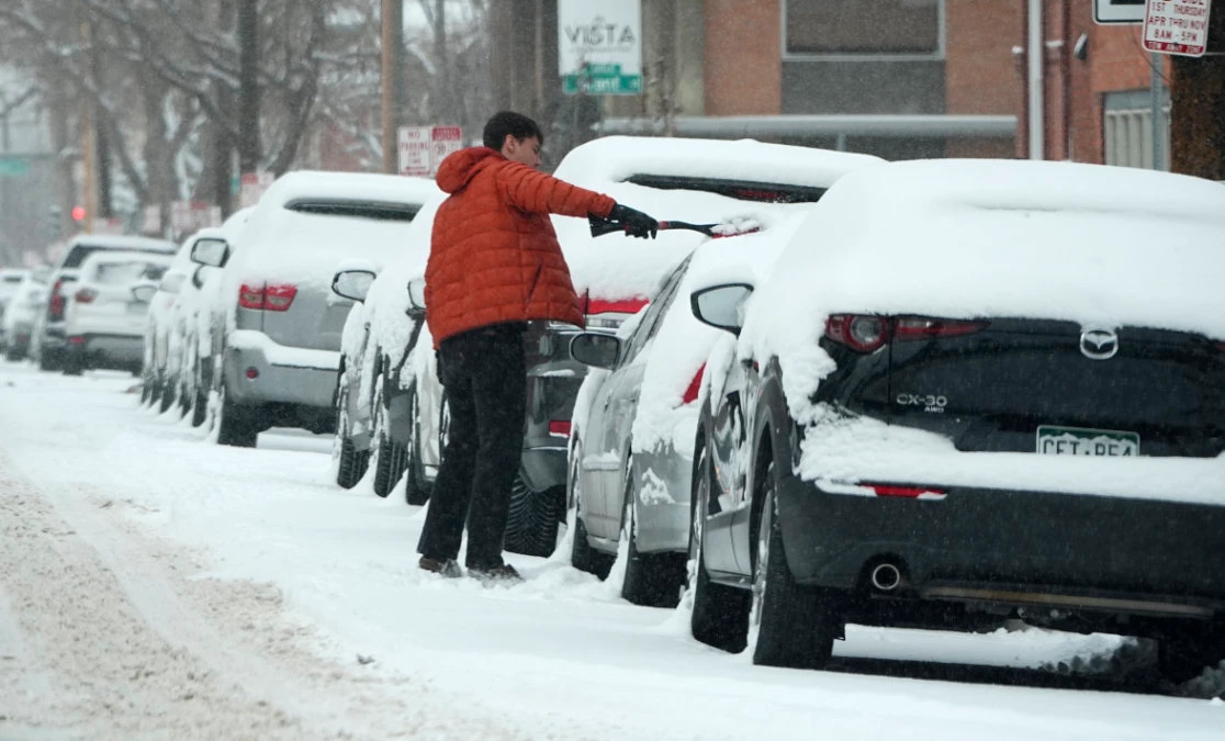 A motorist clears snow off his vehicle parked along First Avenue as a winter storm sweeps over the intermountain West, plunging temperatures into the single digits and bringing along a light snow in its wake Saturday, Jan. 18, 2025, in Denver. (AP)