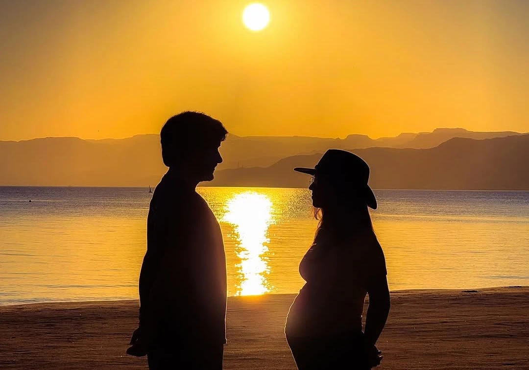 Queen Rania, the princess’s mother, shared the news on Instagram with a photo of the couple at sunset by the beach, highlighting the mother-to-be’s growing belly. (Instagram)