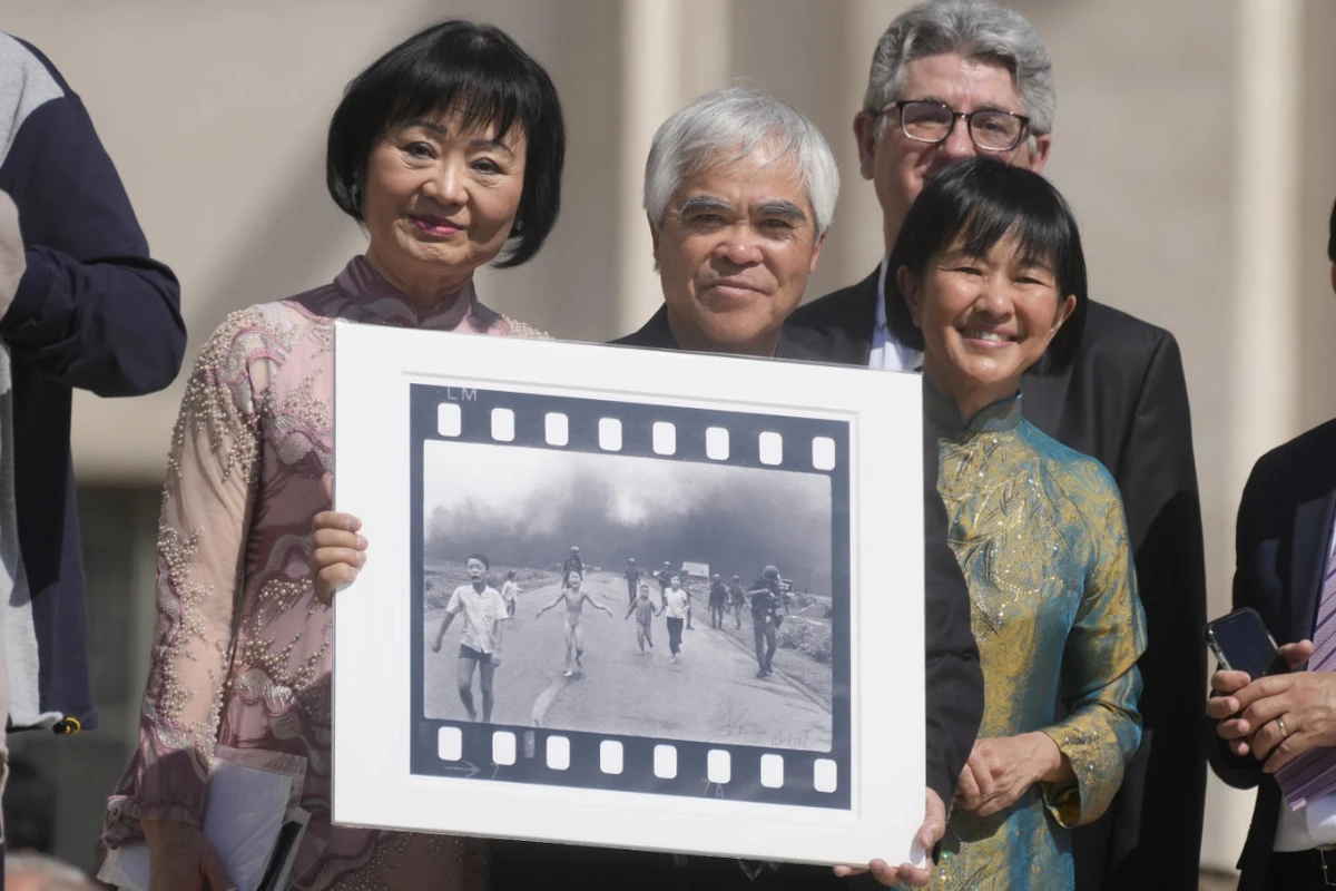 Pulitzer Prize-winning photographer Nick Ut, center, flanked by Kim Phuc, left, holds the “Napalm Girl”, his Pulitzer Prize winning photo, as they wait to meet with Pope Francis during the weekly general audience in St. Peter‘s Square at The Vatican, May 11, 2022. (AP)