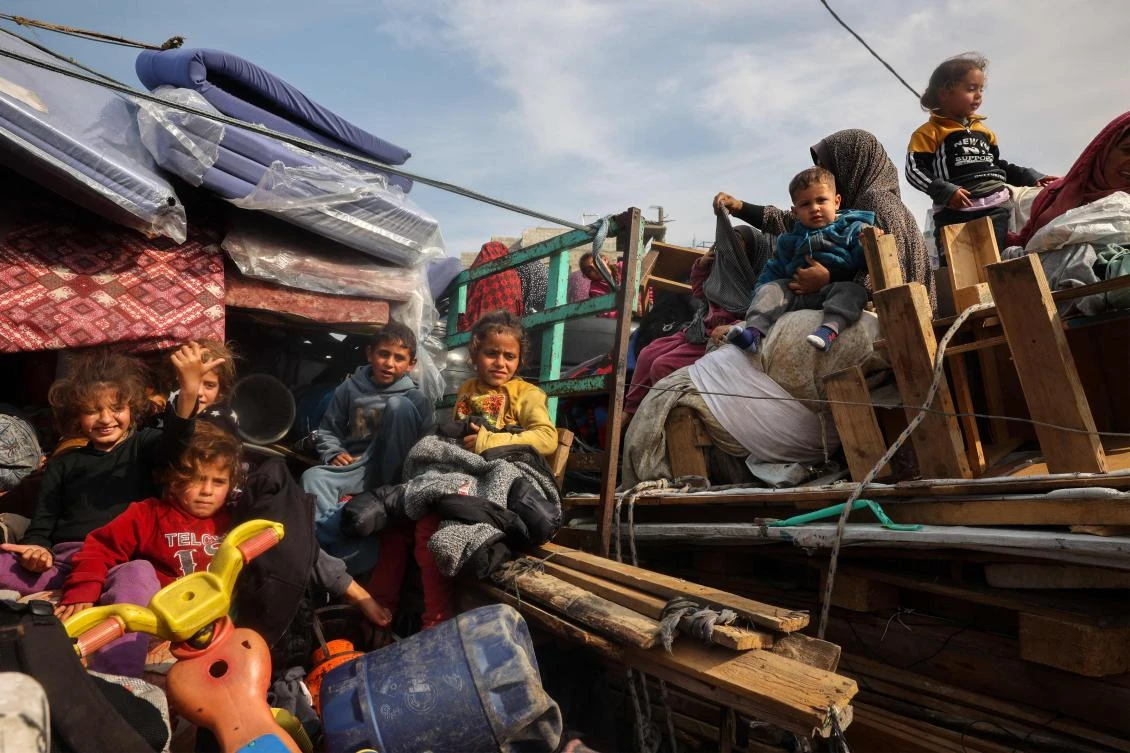 Displaced Palestinian children sit on the back of trucks waiting along Salah Al-Din road in Nuseirat as people make their way to the northern part of the Gaza strip on Jan. 28, 2025. (AFP)
