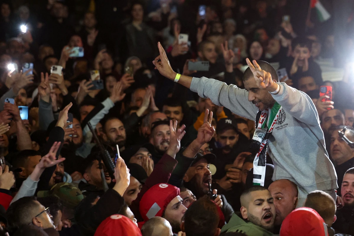 Former Palestinian prisoner Zakaria Zubeidi, 49, flashes victory signs as he is lifted by the crowd upon arrival with others to Ramallah after their release by Israel, Jan. 30 (AFP)