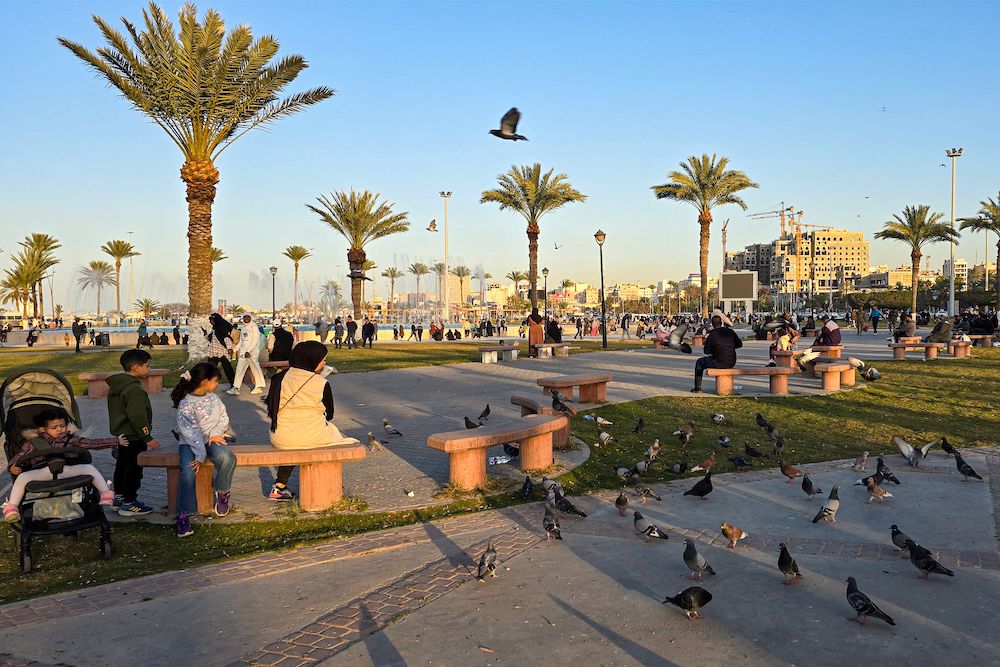Pigeons walk near people sitting at the Martyrs' Square in Libya's capital Tripoli on Feb. 15. (AFP)