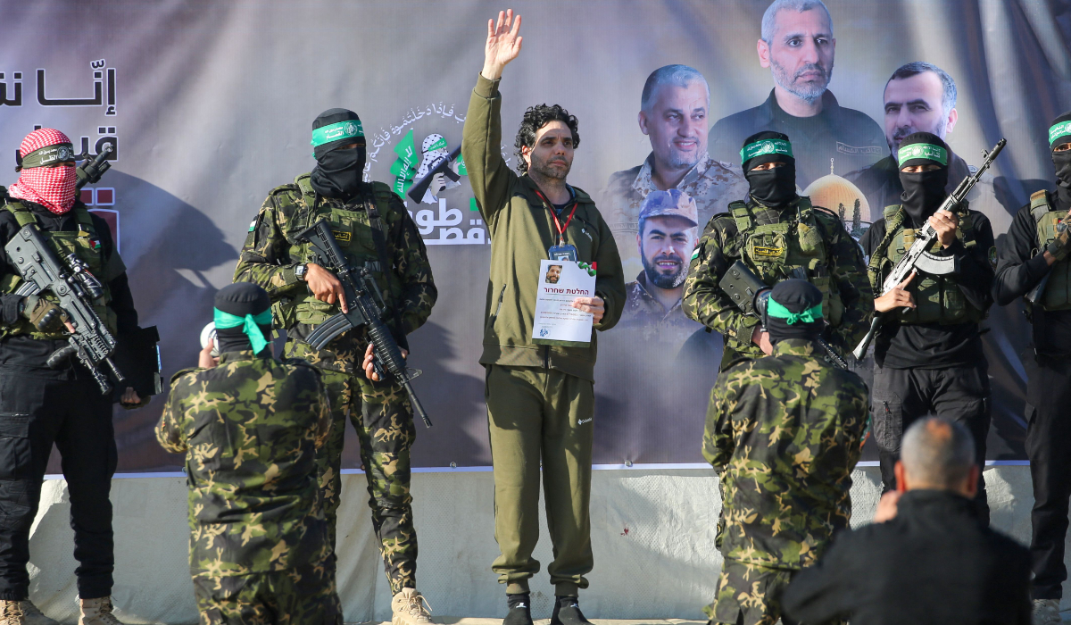 Palestinian militant group Hamas fighters escort Israeli-French hostage Ofer Kalderon on a stage before handing him over to a Red Cross team in Khan Yunis on February 1, 2025, as part of fourth hostage-prisoner exchange. (AFP)