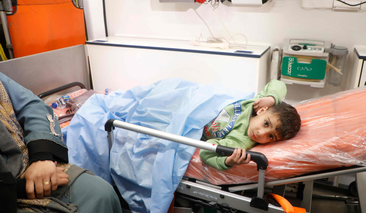 A Palestinian child, transported with a relative from the Gaza Strip, arrives in Egypt through Rafah border crossing on February 1, 2025, as Palestinian patients are transported out of the Palestinian strip as the key gateway reopened as part of a ceasefire deal. (AFP)