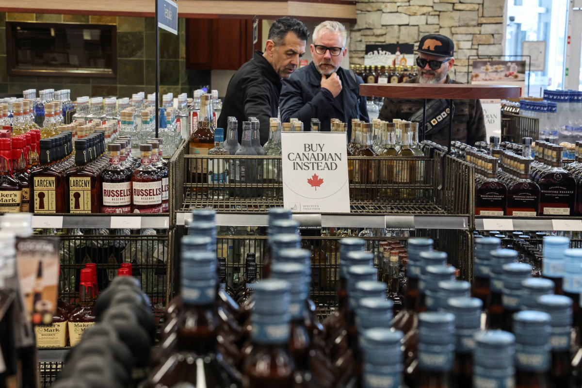 People look on as empty shelves remain with signs "Buy Canadian Instead" after the top five US liquor brands were removed from sale at a B.C. Liquor Store in Vancouver, on February 2, 2025, as part of a response to US President Donald Trump's 25% tariffs on Canadian goods. (Reuters)
