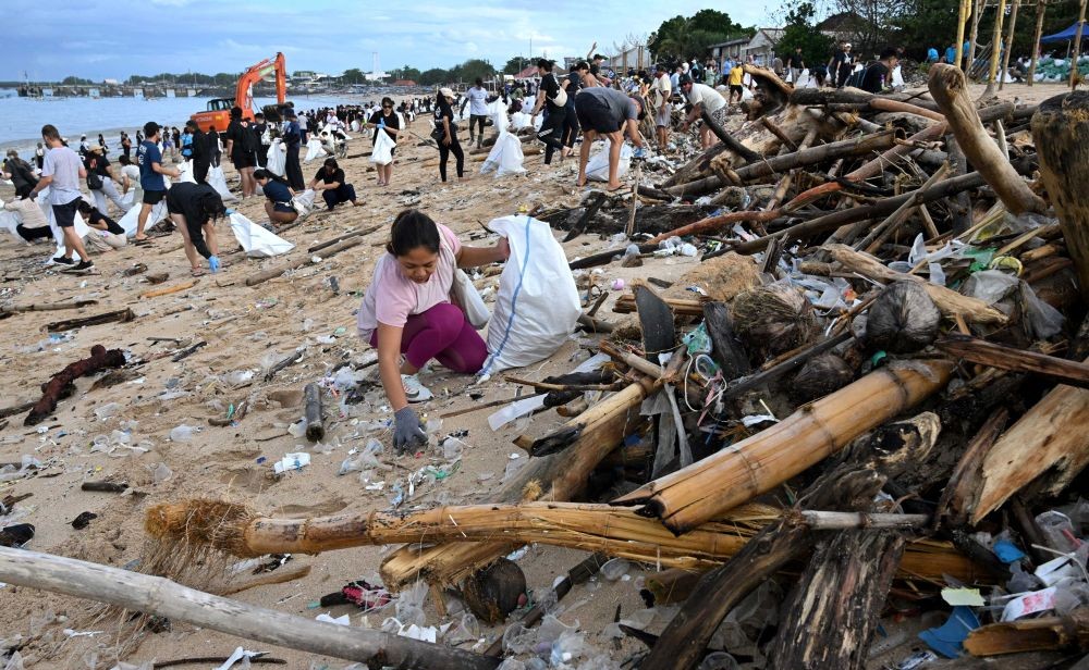 Participants and volunteers remove plastic waste and other garbage washed ashore at a beach in Indonesia's Bali island on Jan. 4, 2025. (AFP)