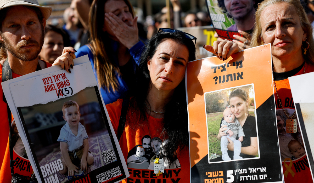A woman carries placards with pictures of Ariel Bibas, who has been held in Gaza since the deadly October 7, 2023 attack, on the day of the release of hostages as part of a ceasefire deal in Gaza between Hamas and Israel, in Tel Aviv, Israel February 1, 2025. (REUTERS)