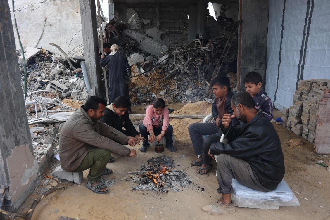 Palestinians warm themselves by a fire inside a heavily damaged building at Saftawi street in Jabalia, in Gaza, on Feb. 5, 2025 during a ceasefire deal in the war between Israel and Hamas. (AFP)