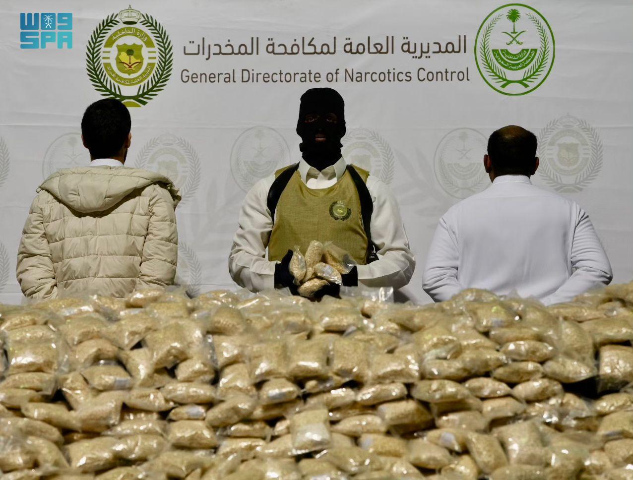 A photo released by the General Directorate of Narcotics Control shows seized illegal drugs and two suspects in civilian clothes involved in smuggling, Feb. 5 (SPA)
