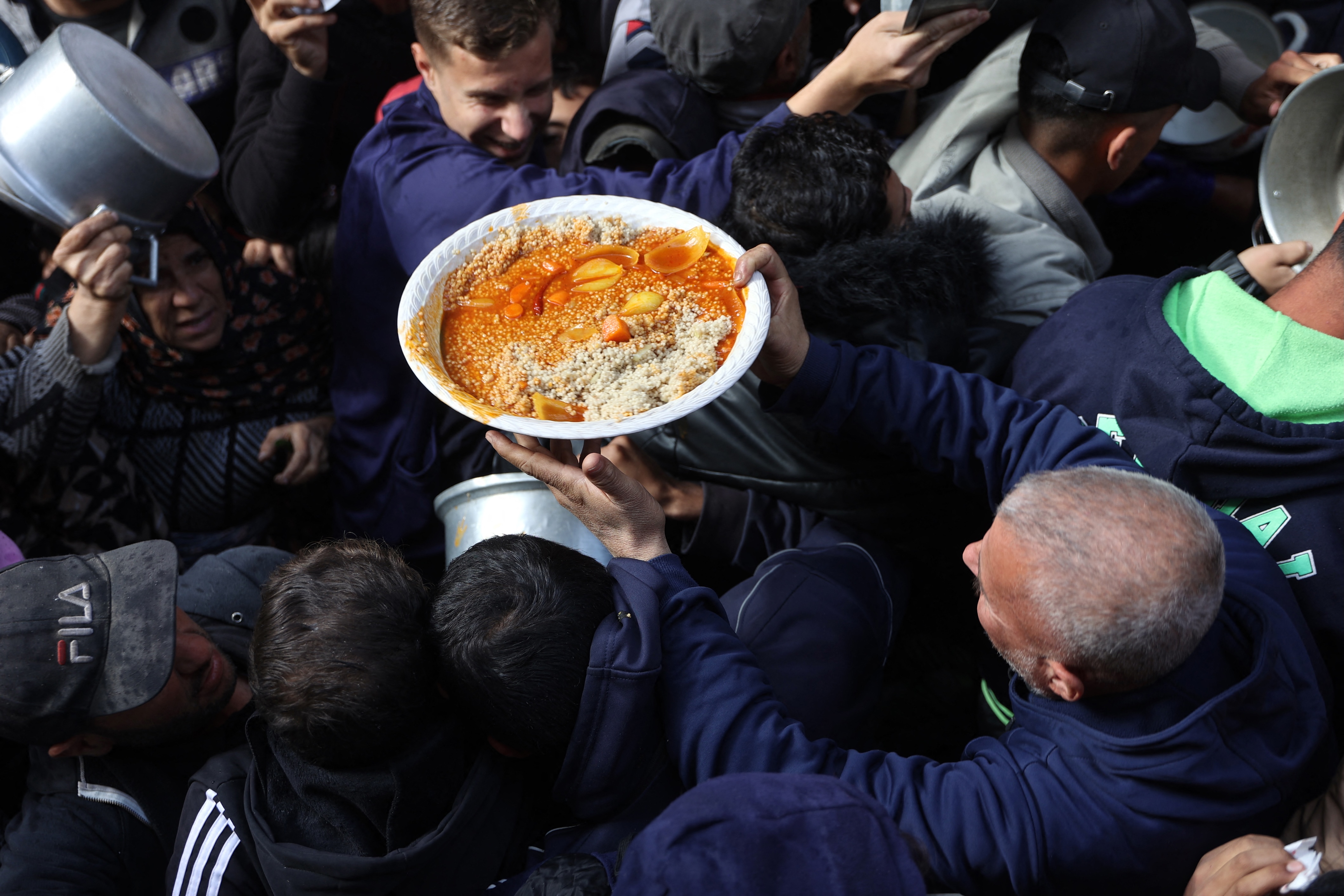 A man carries a plate of food as Palestinians collect humanitarian aid in al-Shati camp near Gaza City, Dec. 26, 2024. (AFP)