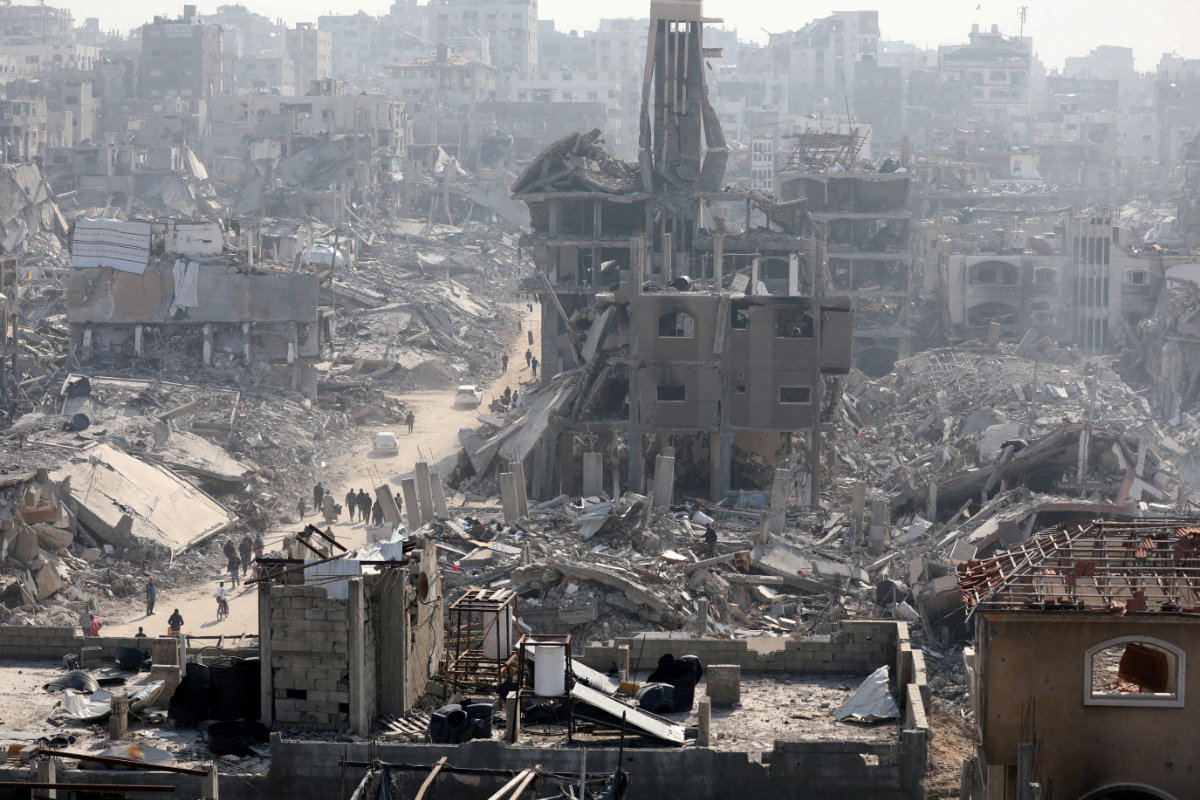 People walk past the rubble of destroyed buildings in Jabalia, northern Gaza Strip, on January 30, 2025. (REUTERS/)