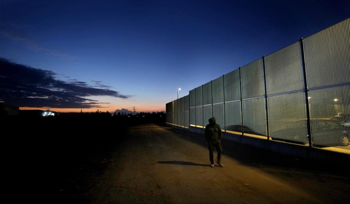 A man walks by the fence at the Pournara migrant reception center in Kokkinotrimithia outside of capital Nicosia, Cyprus, Wednesday, Jan. 24, 2024. (AP)