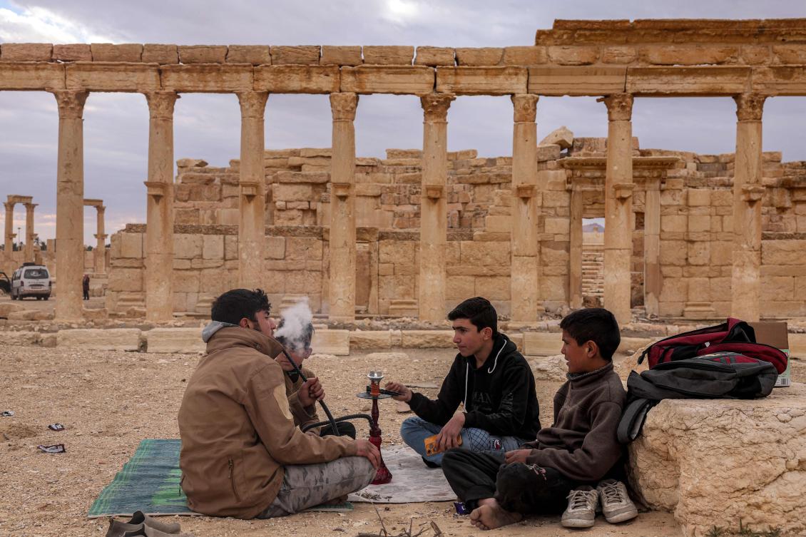 Youths smoke shisha by the Great Colonnad at the ancient ruins of Palmyra in central Syria, Feb. 7, 2025. (AFP)