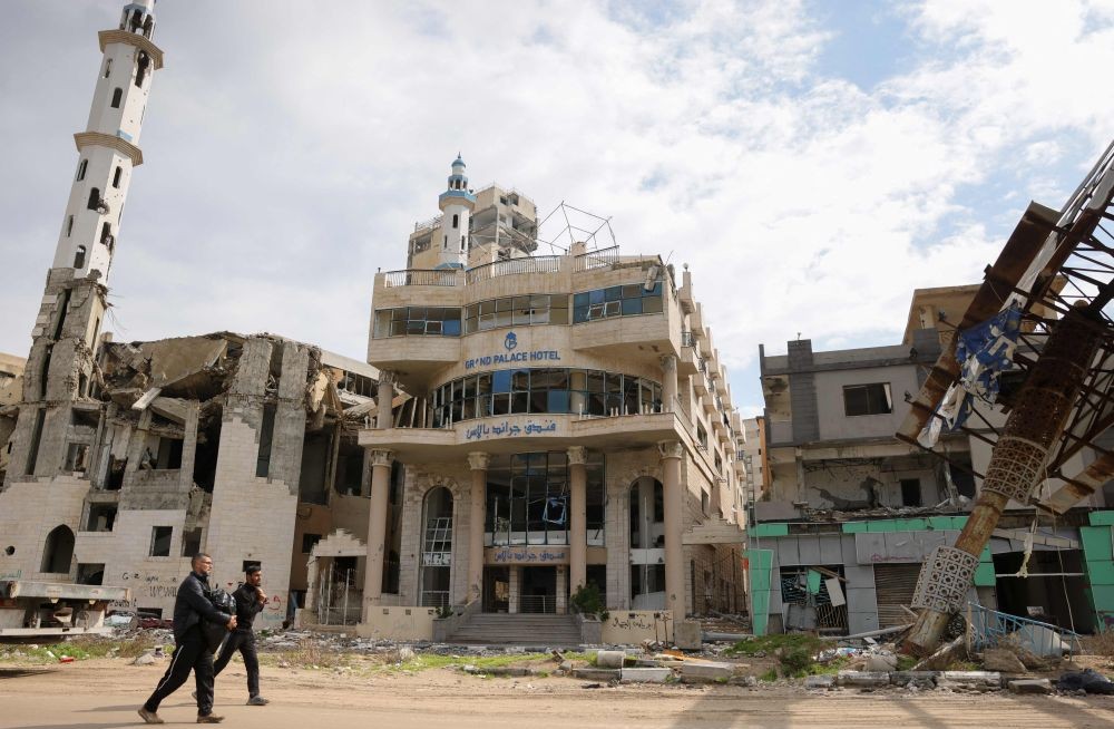 Men walk past the heavily-damaged Grand Palace Hotel in western Gaza City, on February 11, 2025, amid the current ceasefire deal in the war between Israel and Hamas. (AFP)