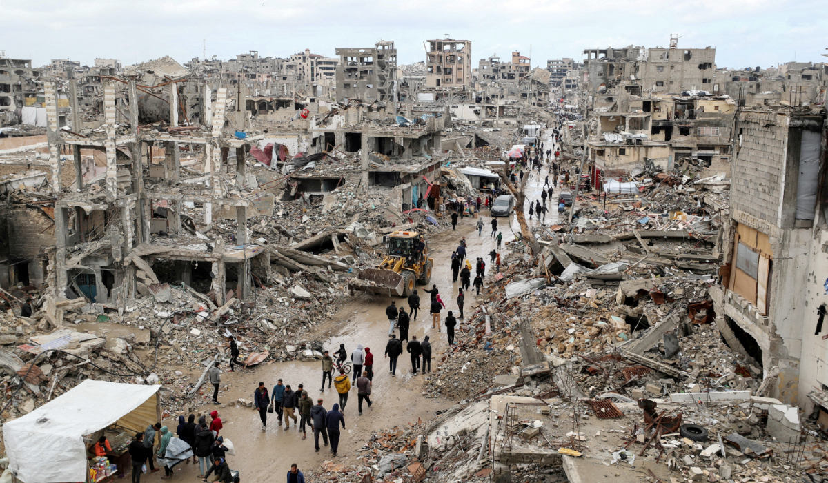Palestinians walk past the rubble of buildings destroyed during the Israeli offensive, on a rainy day, amid a ceasefire between Israel and Hamas, in Gaza City February 6, 2025. (REUTERS)