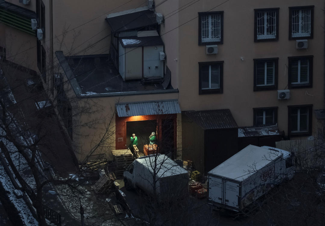 Supermarket staff smoke as they wait for delivery trucks during an early morning air-raid alert in Kyiv on Feb. 11, 2025. (Reuters)