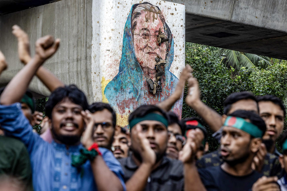 Sheikh Hasina, who fled into exile in neighboring India, has already defied an arrest warrant to face trial in Bangladesh for crimes against humanity. Students protest near a vandalized mural of Sheikh Hasina in Dhaka on Aug. 12, 2024. (AFP)