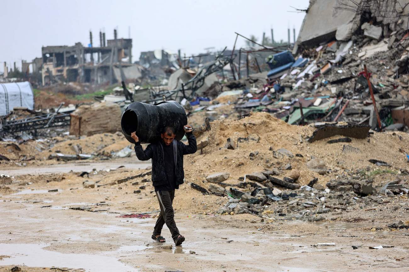 A Palestinian man carries a water tank amid the devastation in Beit Hanun in the northern Gaza Strip on February 12, 2025. (AFP)
