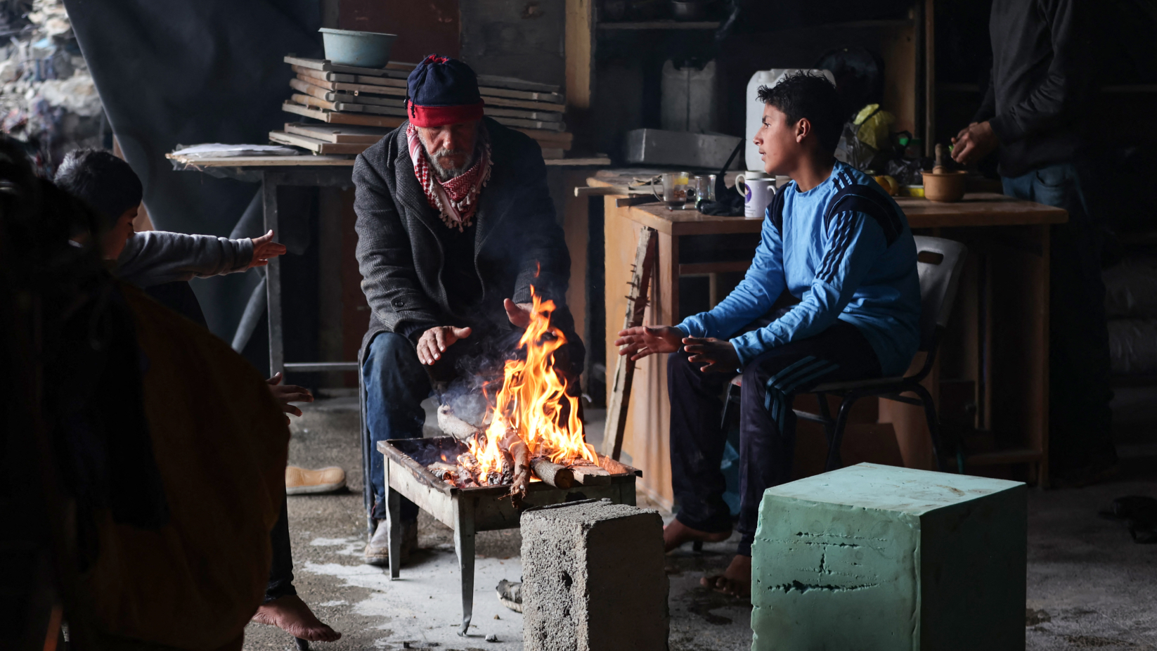 Palestinians warm themselves around a fire inside a makeshift shelter in Beit Hanun in the northern Gaza Strip, Feb. 12, 2025. (AFP)