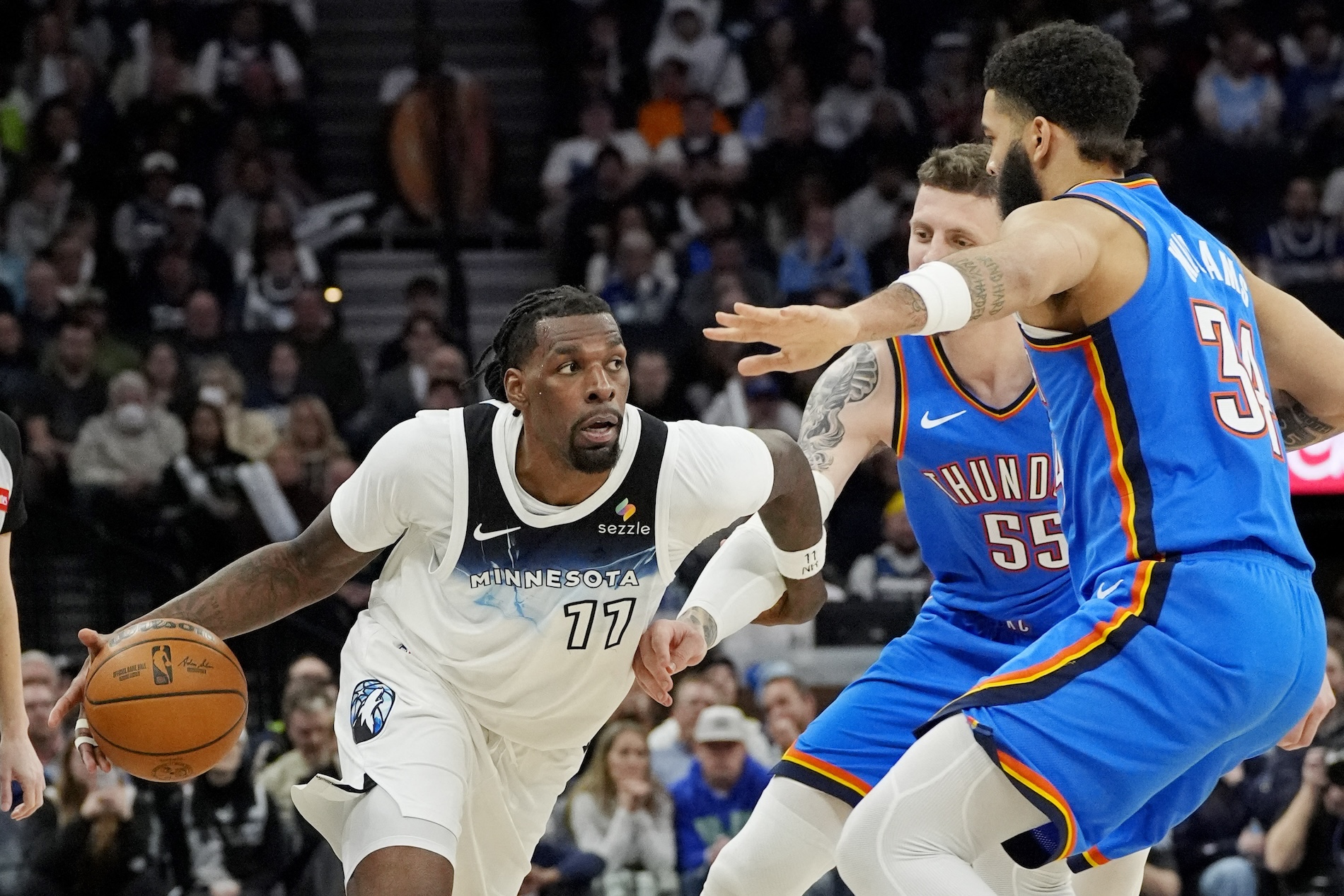 Minnesota Timberwolves center Naz Reid dribbles around Oklahoma City Thunder center Isaiah Hartenstein (55) and guard Kenrich Williams in the fourth quarter of an NBA Game at Target Center Thursday. (USA TODAY Sports)