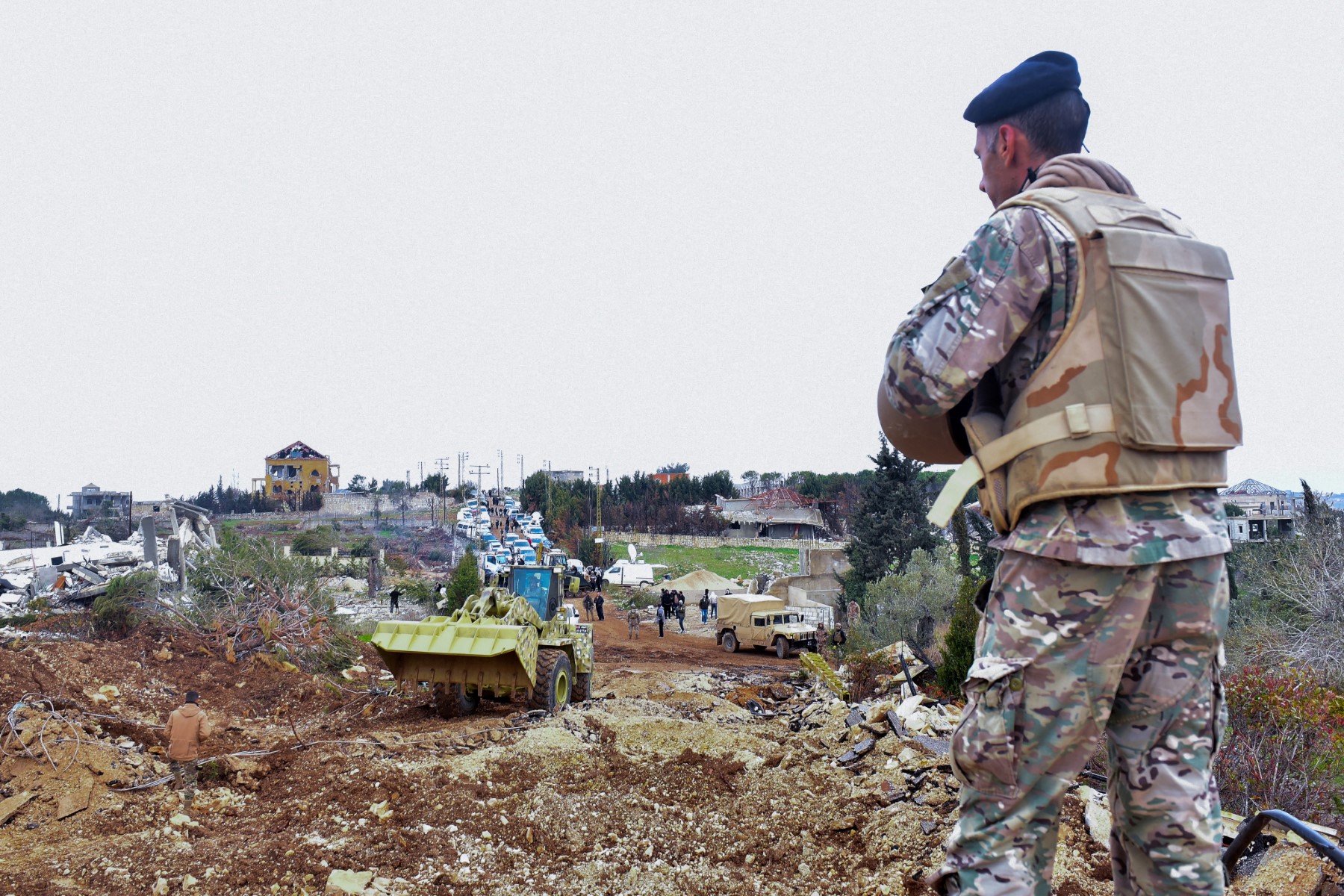 A Lebanese soldier stands guard after army deployment as a bulldozer opens a road for the residents of the southern village of Rubb Thlathin to return to their town on February 9, 2025.(AFP)