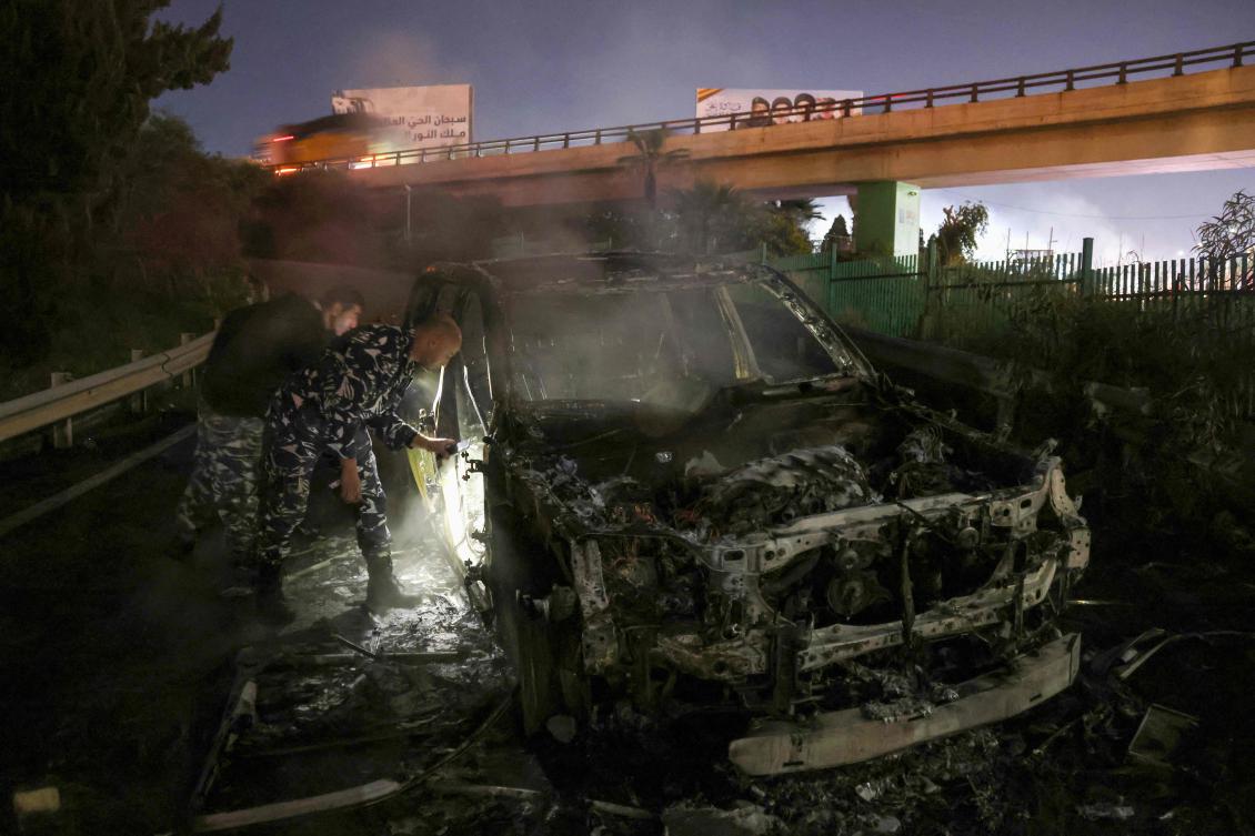 Policemen inspect the burnt remains of a UNIFIL vehicle, set ablaze by protesters, on the road leading to Beirut’s international airport on Feb. 14, 2025. (AFP)