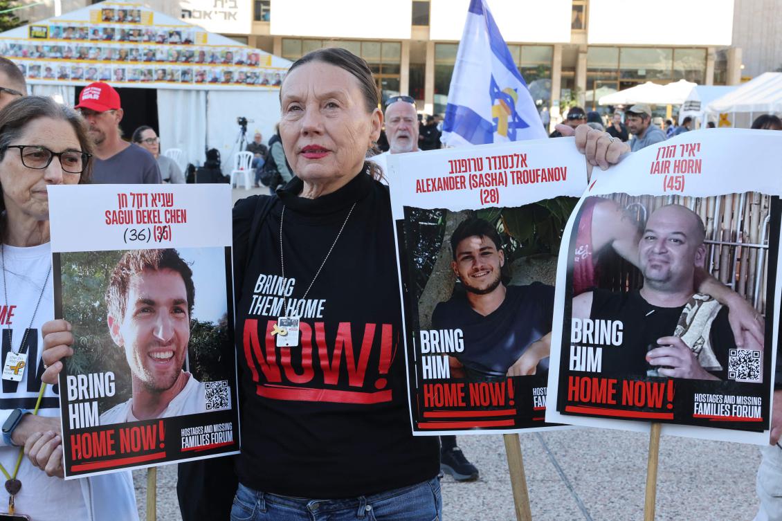 A woman holds pictures of Israeli hostages in Tel Aviv on Feb. 15, 2025 as families gather in the city’s Hostages Square while waiting for the release by Hamas of three double-nationals held in the Gaza Strip since the Oct. 7, 2023. (AFP)