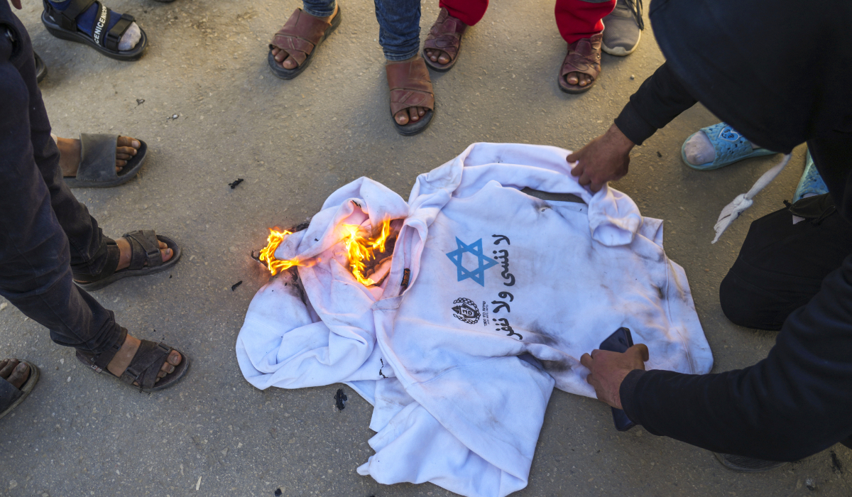 A crowd burns the shirts worn by freed Palestinian prisoners in Khan Younis, Gaza Strip, Saturday, Feb. 15, 2025, as they arrive in Gaza after being released from an Israeli prison following a ceasefire agreement between Hamas and Israel. (AP)