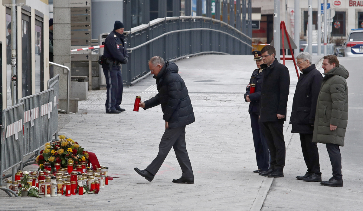 Austria's Interior Minister Gerhard Karner (L) places a candle on February 16, 2025 at the site where a man randomly attacked passers-by with a knife and stabbed to death a teenager and wounded five other people in Villach, Austria. (AFP)