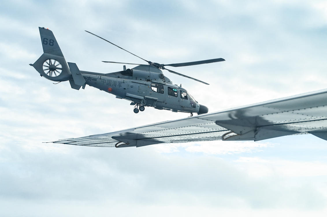 An aircraft identified as a Chinese navy helicopter, left, flies near a Philippine government fisheries aircraft during an aerial reconnaissance flight at Scarborough Shoal in the South China Sea on Feb. 18, 2025. (AFP)